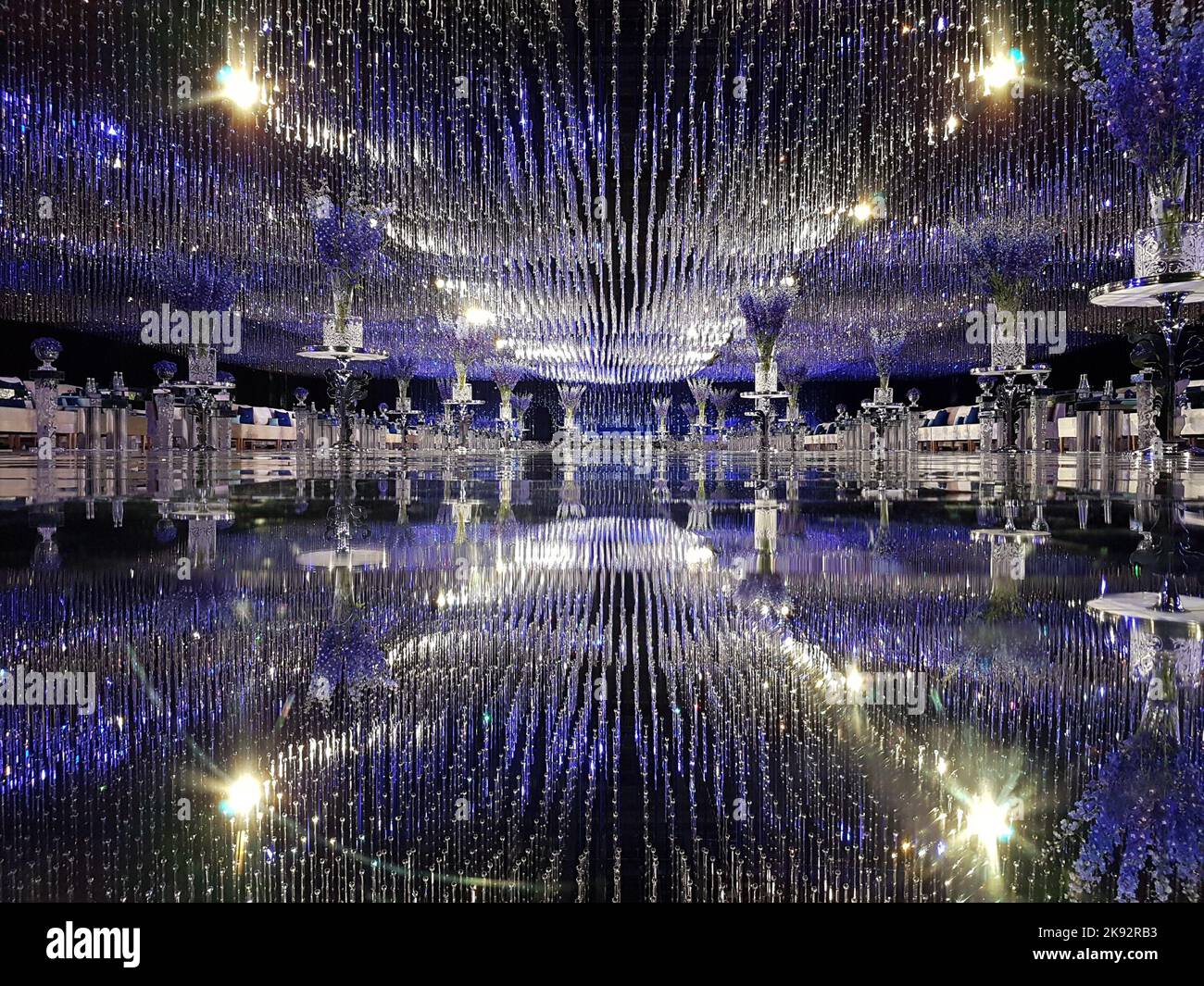 Elegante design della sala per matrimoni degli Emirati. Interni della reception di lusso. Bella messa a punto con cristalli scintillanti, vetro riflettente, decorazioni viola accenti. Foto Stock