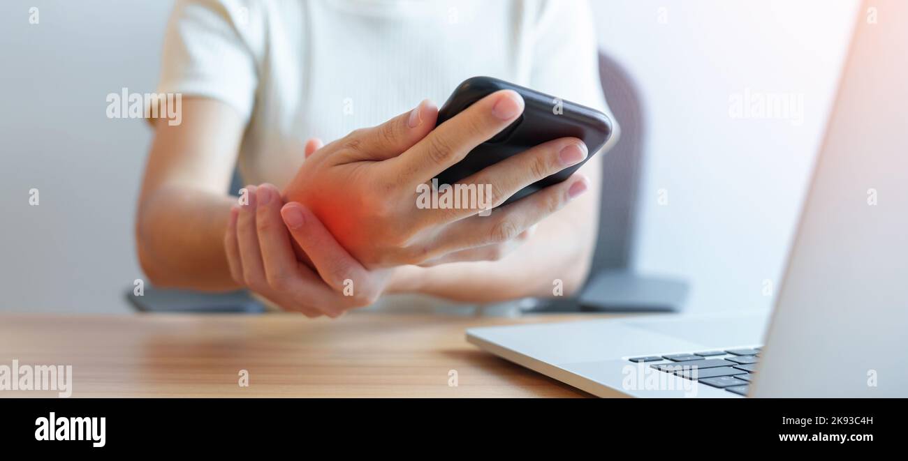 Donna che ha dolore al polso quando si utilizza il telefono cellulare durante il lavoro a lungo sul posto di lavoro. La tenosinovite di de Quervain, ergonomica, sindrome del tunnel carpale Foto Stock