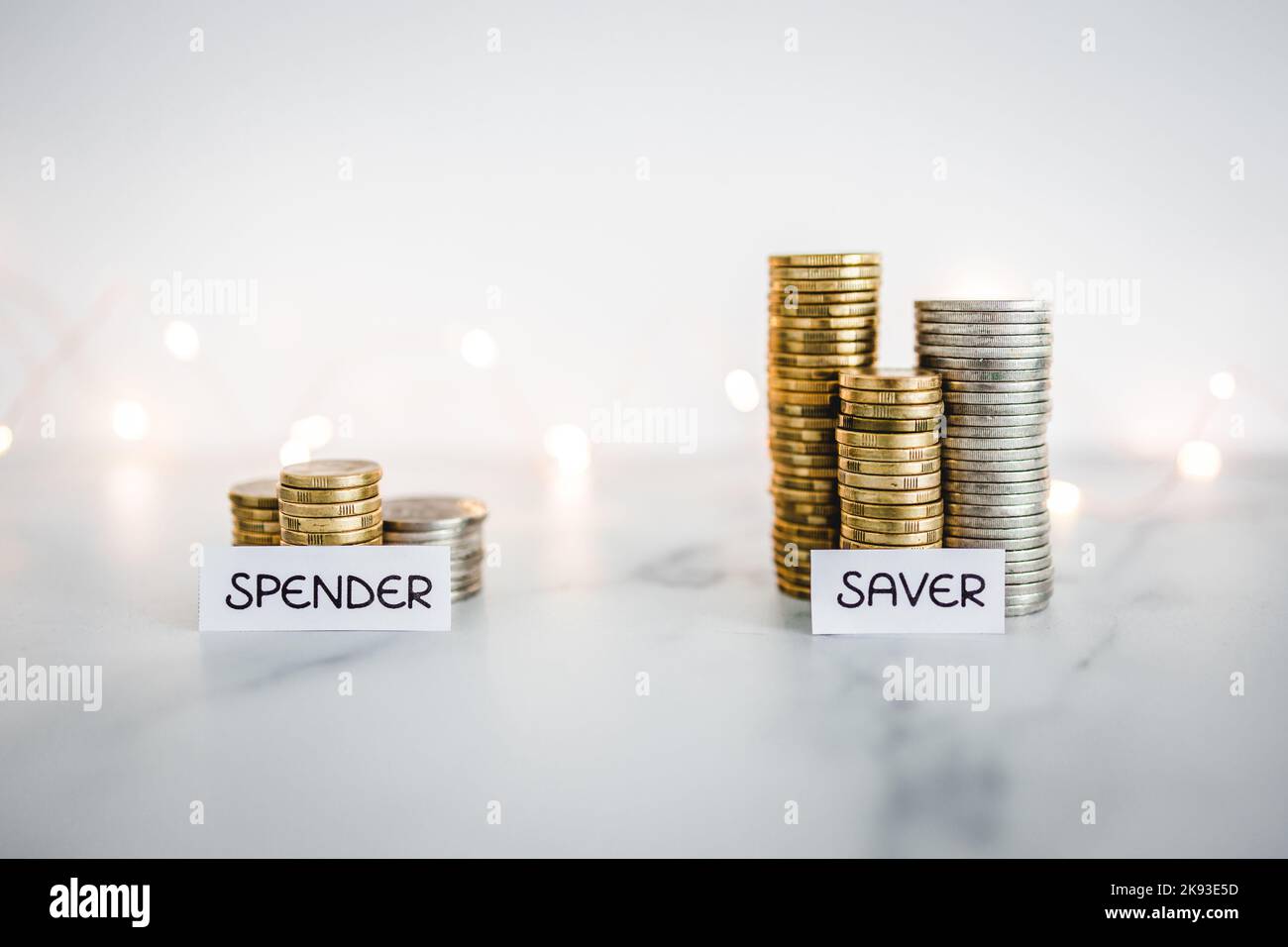Testo risparmiatore vs spender davanti a grandi e piccole pile di monete. Immagine concettuale sul denaro, l'abbondanza e la ricchezza Foto Stock