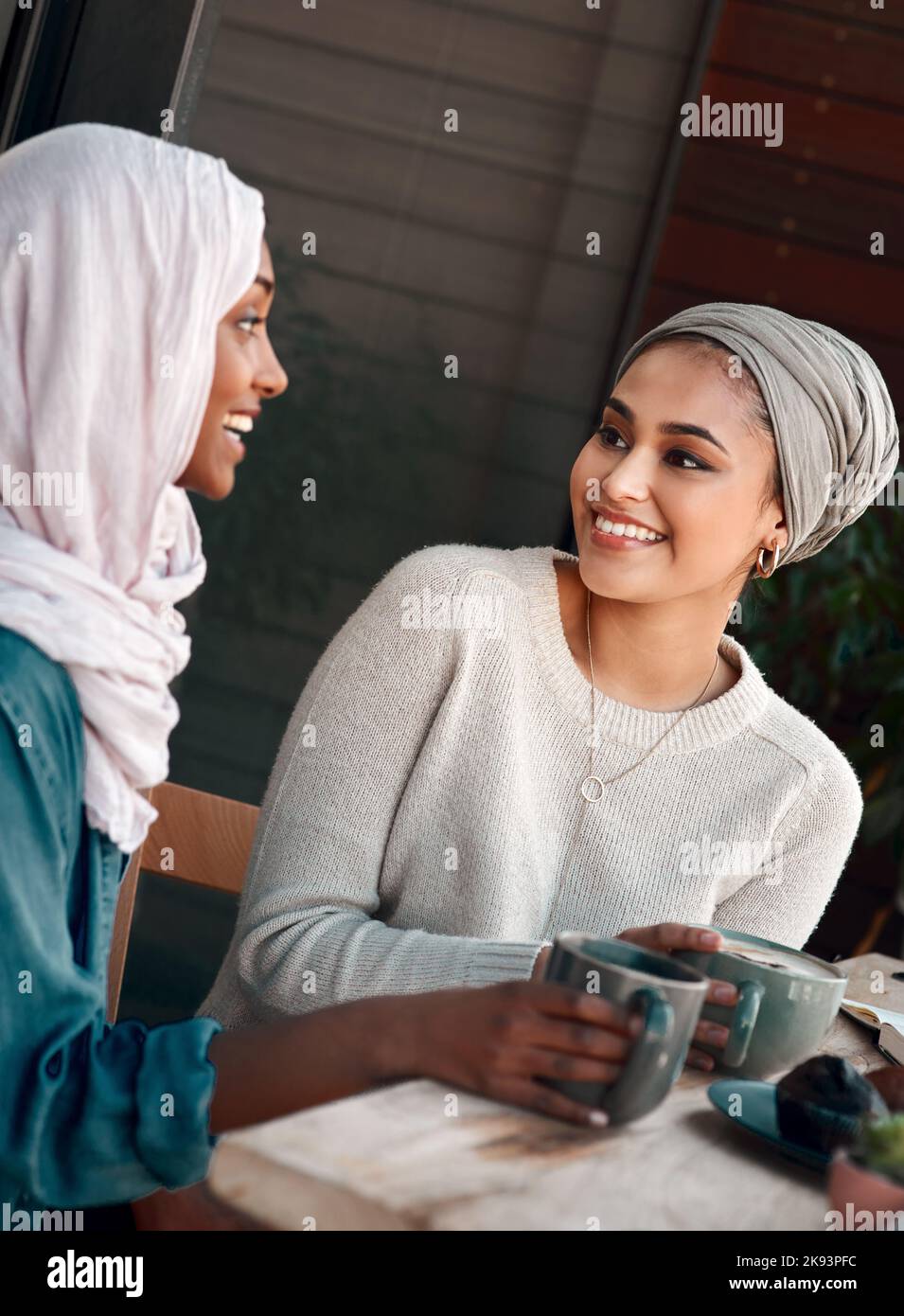 Parla di una buona data del caffè. Due giovani fidanzate chiacchierano in un bar mentre si vestono in hijab. Foto Stock