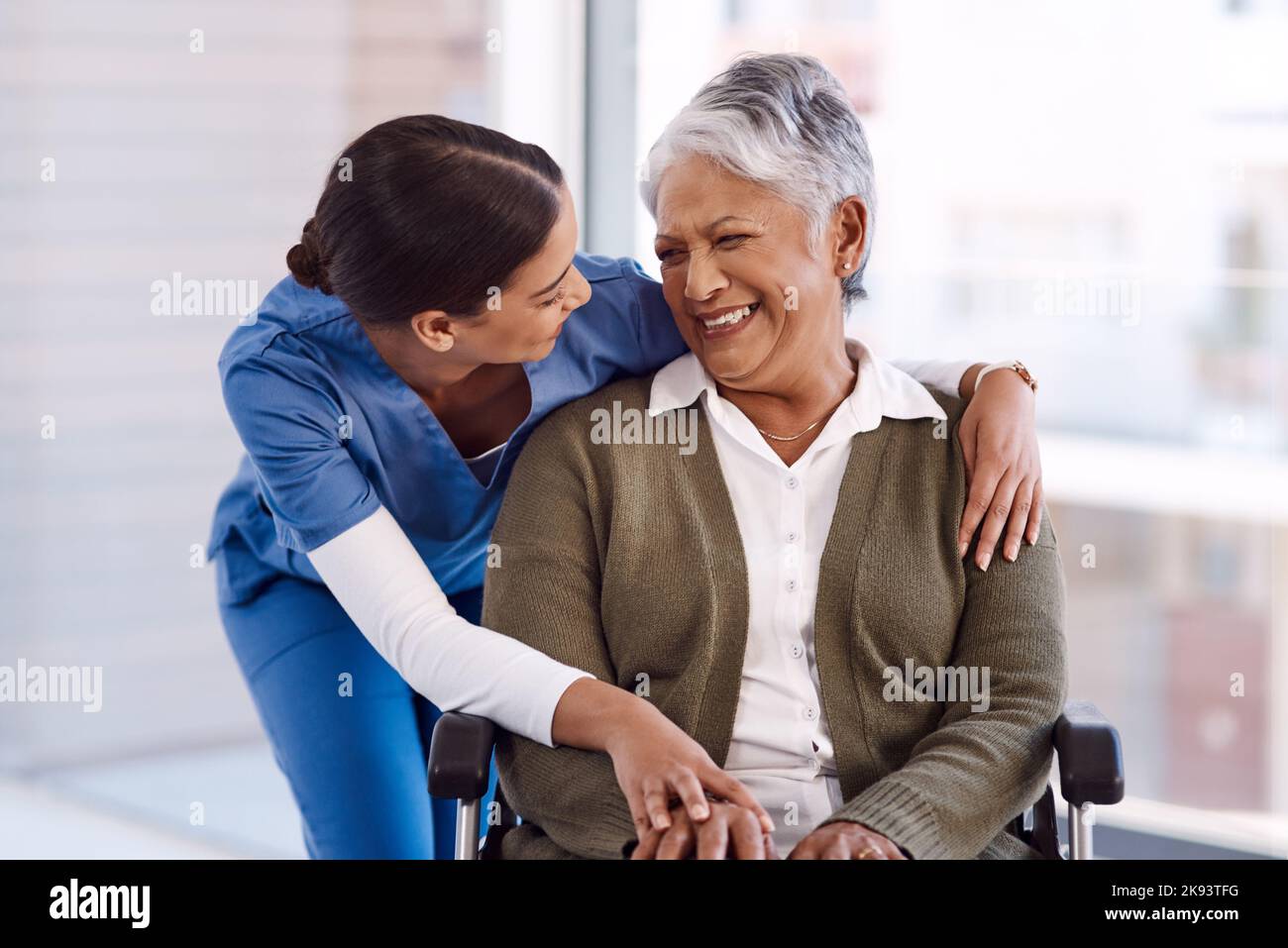 Ha una natura molto gentile con i suoi pazienti: Una giovane infermiera che si prende cura di una donna anziana su una sedia a rotelle. Foto Stock