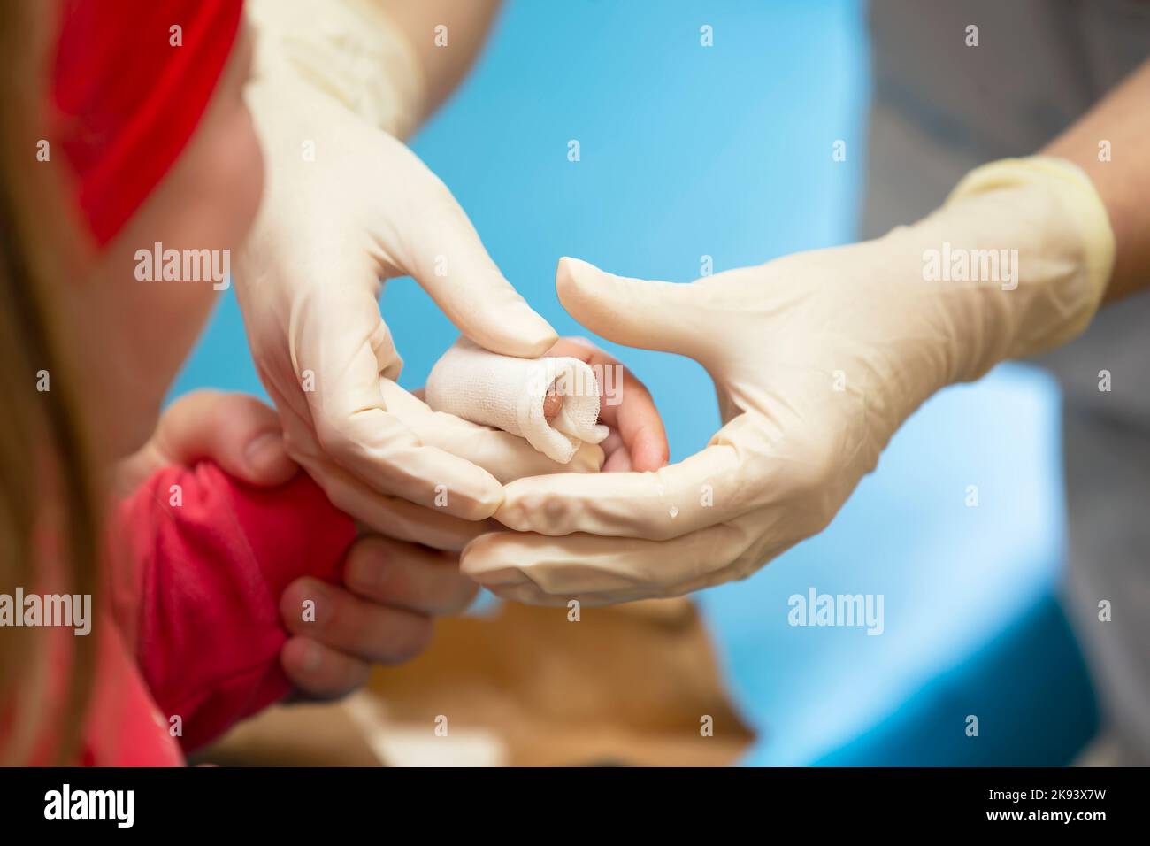 Le mani del medico bendano il dito dolente con un bendaggio del bambino. Lesioni e ferite al dito nei bambini Foto Stock