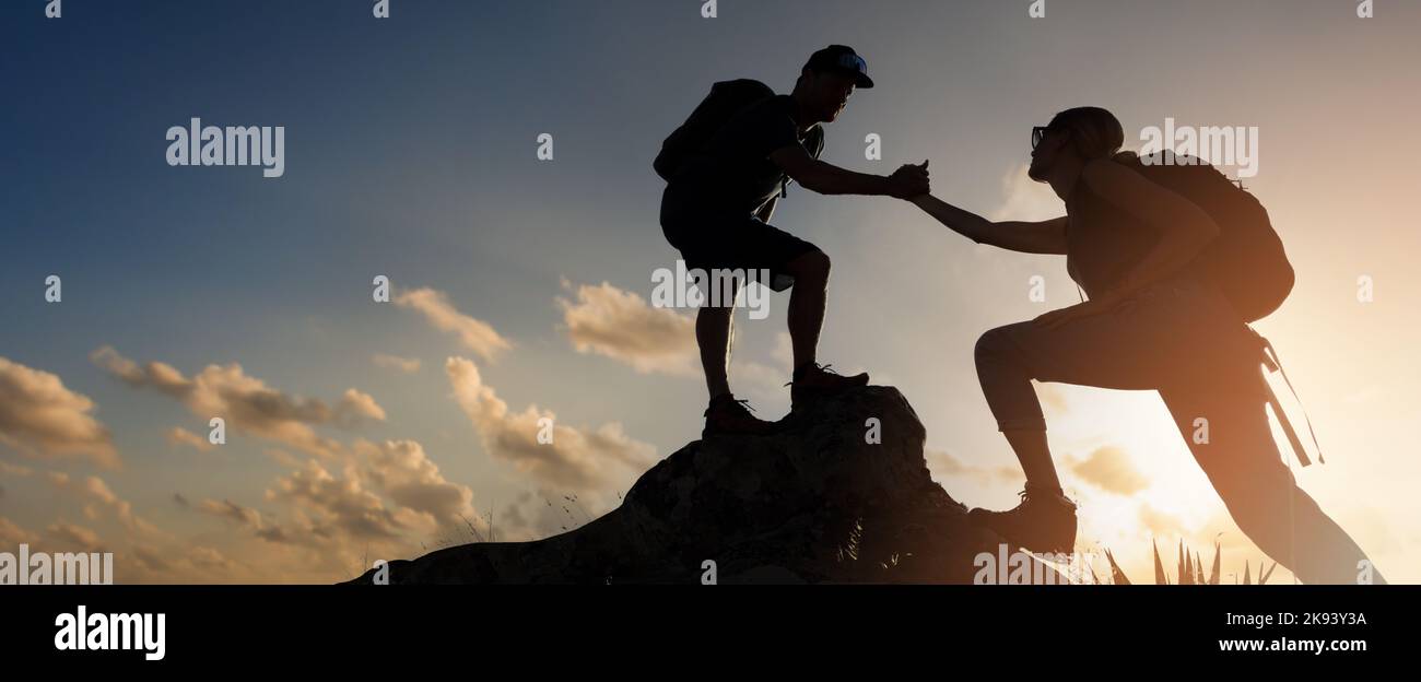 gli escursionisti si arrampicano sulla scogliera di montagna al tramonto. dare una mano. concetto di lavoro di squadra e assistenza. banner con spazio copia Foto Stock