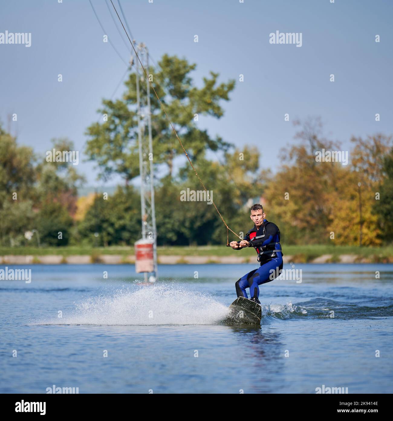 Wakeboarder surf sul lago. Giovane surfista che si diverte a prendere il wakeboarding nel parco della funivia. Sport acquatici, attività all'aperto. Foto Stock
