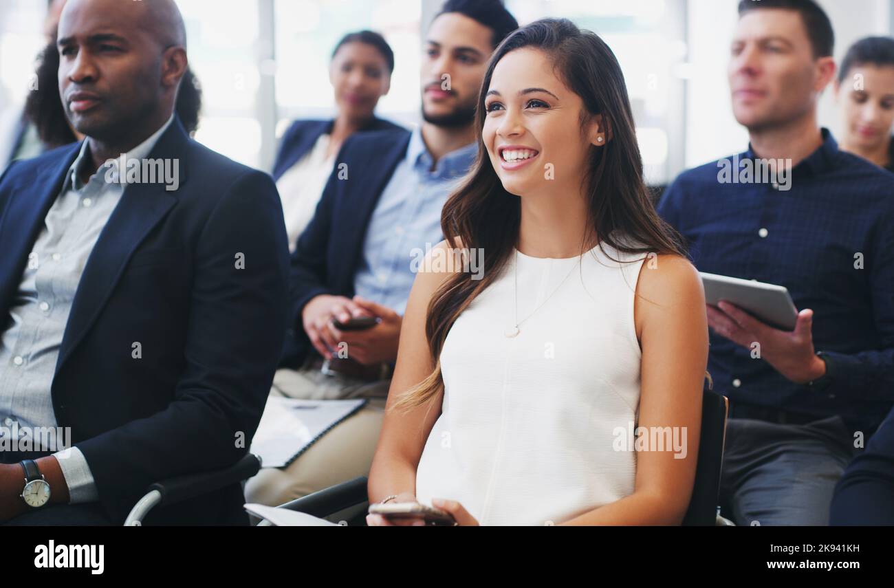 Che cosa fa un nuovo prodotto ha bisogno dei clienti potenziali desiderosi. Una giovane donna felice d'affari seduta nel pubblico di una conferenza di affari. Foto Stock