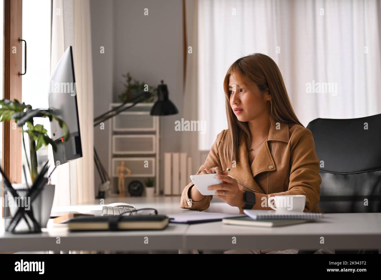 Giovane donna attraente che guarda lo schermo del computer, analizza i dati finanziari, lavora da casa Foto Stock