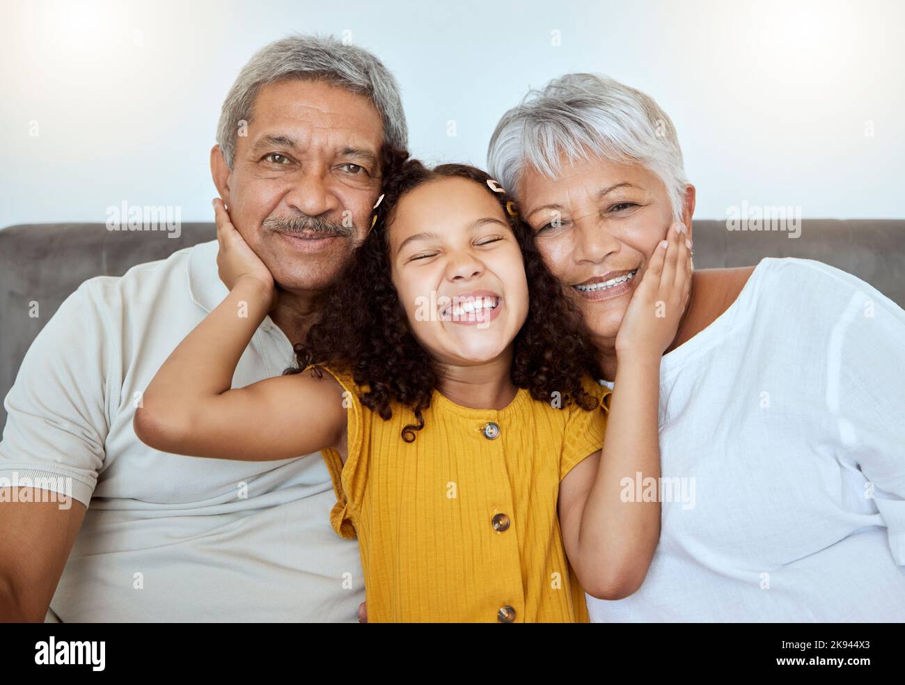 L'amore, i nonni e la ragazza sono felici, sorridono e si legano insieme, abbracciano o insieme sul divano del soggiorno. Nonno, nonna e nipote Foto Stock