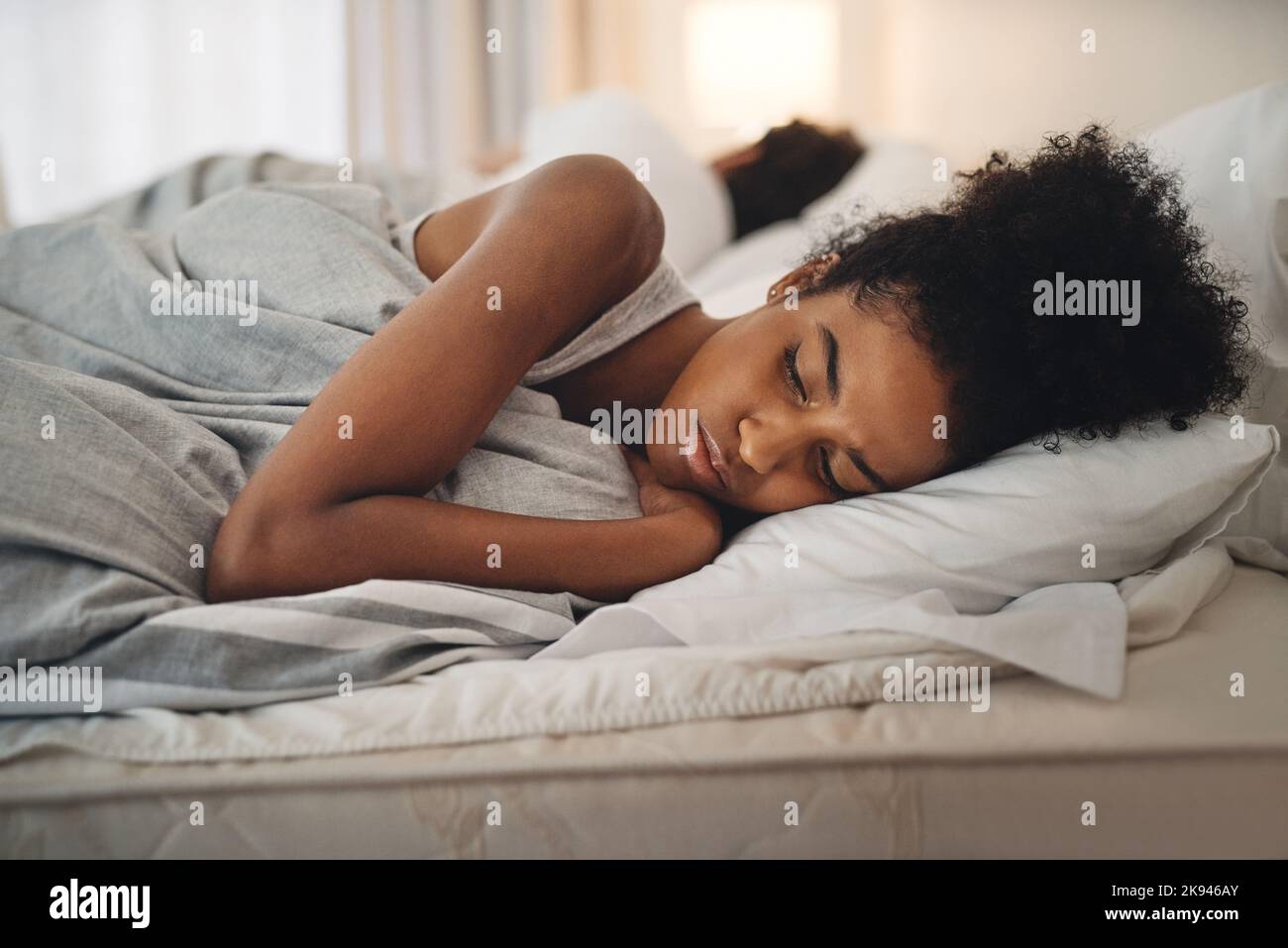 Odio andare a letto con questa sensazione: Una giovane donna che guarda turbata mentre si sdraiava a letto con la sua partner. Foto Stock