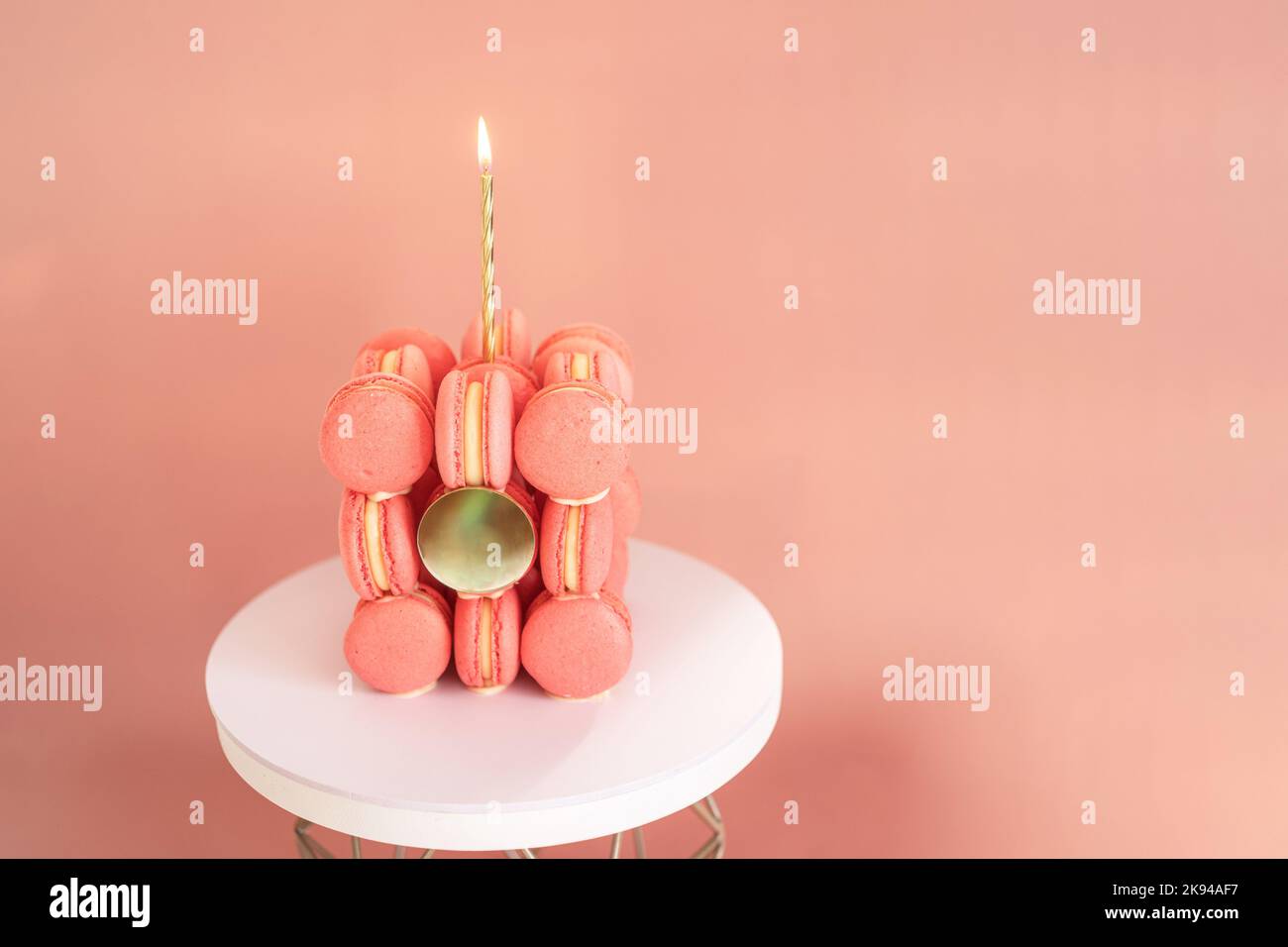 Candele bruciate sulla torta di macaron su sfondo rosa Foto Stock