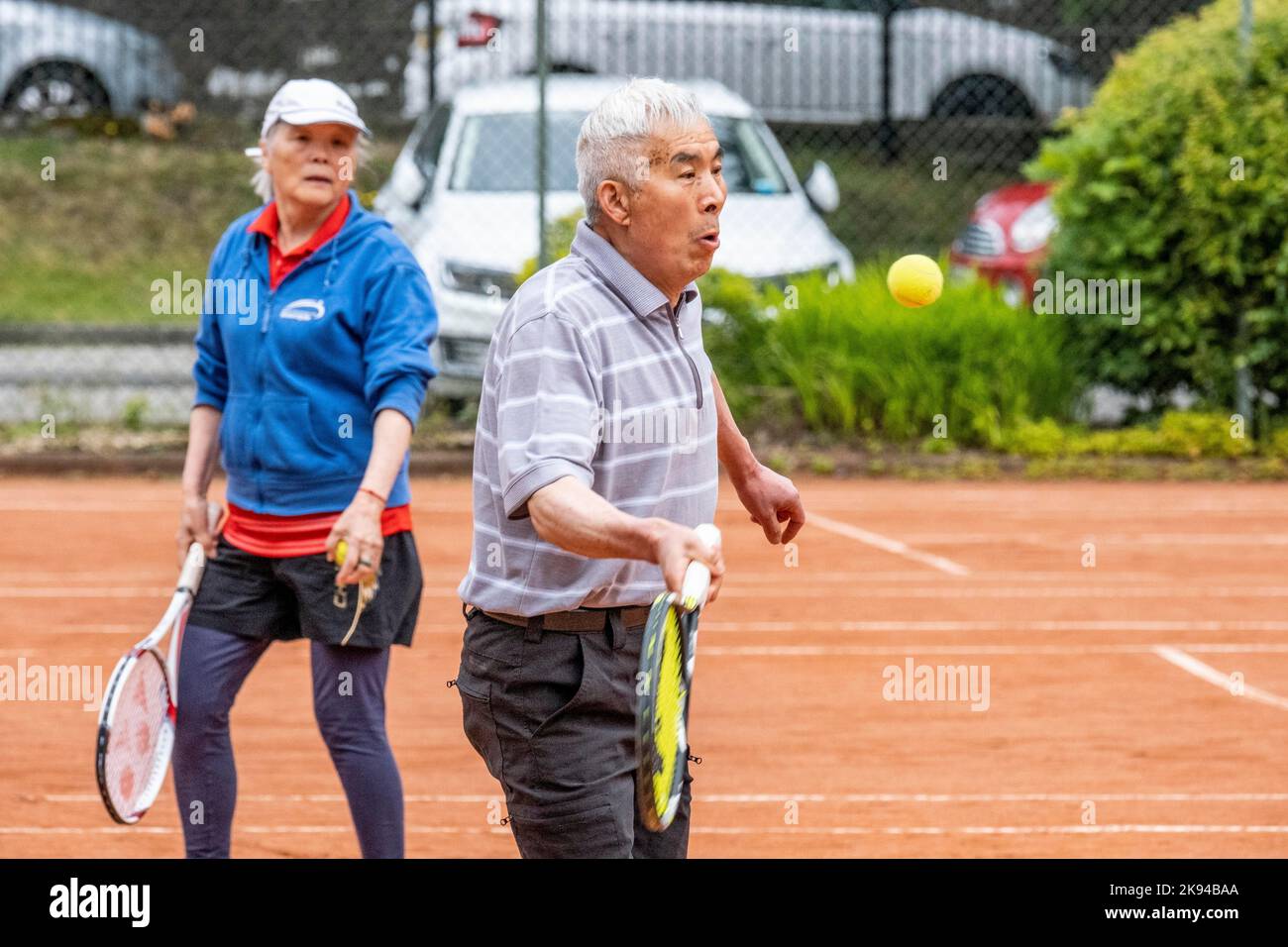 Persone di mezza età e anziane che imparano a giocare a tennis Foto Stock