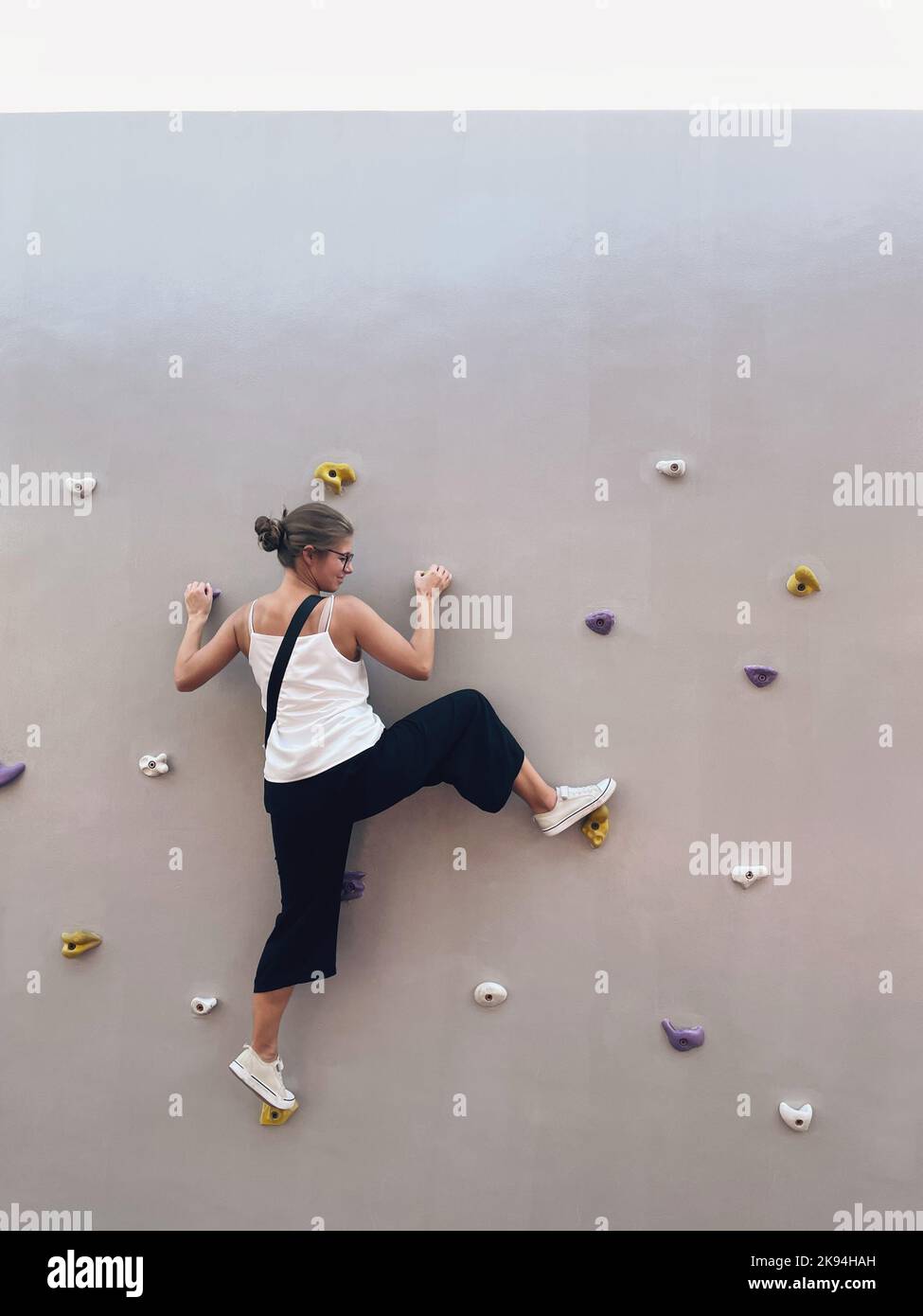 Vista laterale di una giovane femmina in casualità su una parete di arrampicata Foto Stock