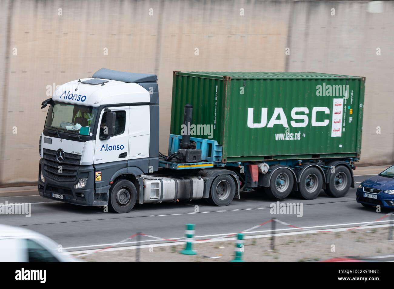 Un camion Mercedes Actros bianco che carica un rimorchio container verde lungo la Ronda Litoral di Barcellona Foto Stock