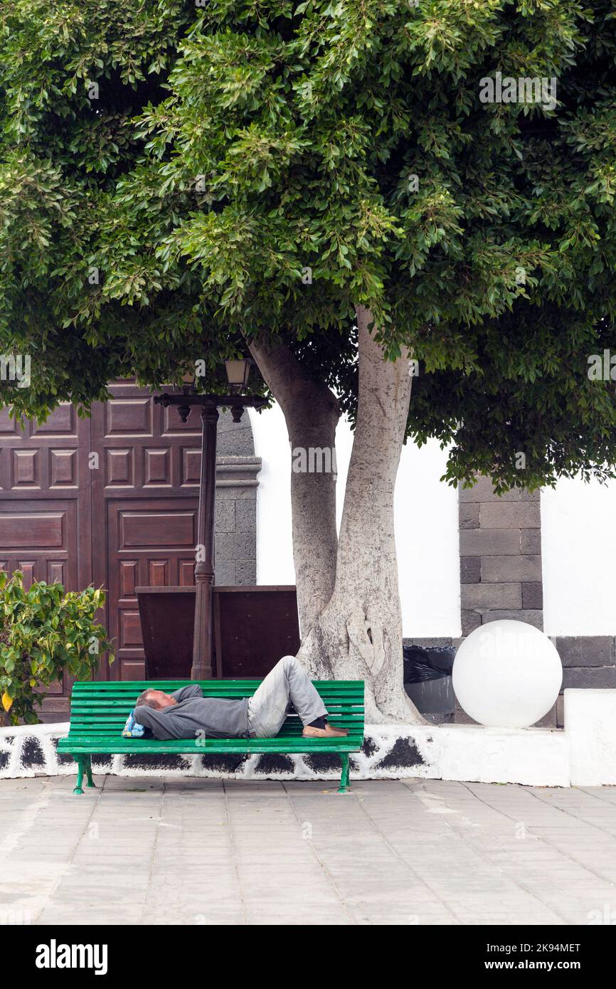 Arrecife, Spagna - 3 aprile 2012: L'uomo tiene una siesta su una panchina ad Arrecife, Spagna. Siesta è il tradizionale orario di riposo da mezzogiorno alle 3:00 in Spagna. Foto Stock