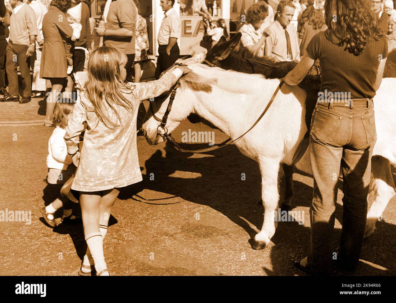 Vintage New Brighton, gite in asino con bambini, 1969, immagine seppia, effetto grana grossa, asino picchiata ragazza Foto Stock