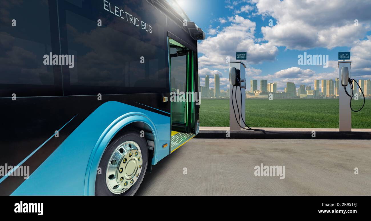 Autobus cittadino elettrico con stazione di ricarica sullo sfondo del paesaggio urbano. Trasporto ecologico e mobilità pulita Foto Stock