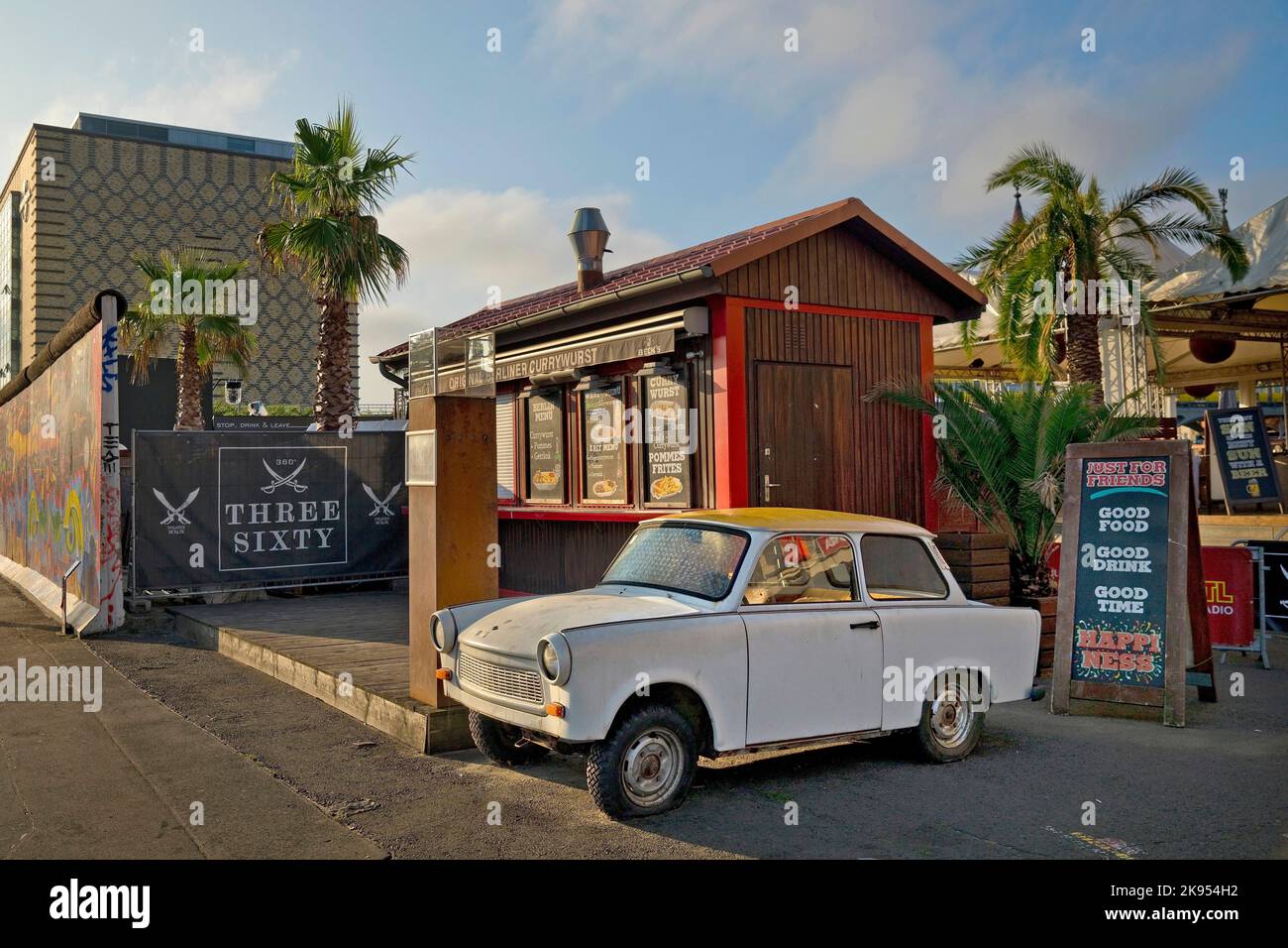 Trabi in uno snack bar con palme a Eierkuehlhaus, East Side Gallery, Germania, Berlino Foto Stock