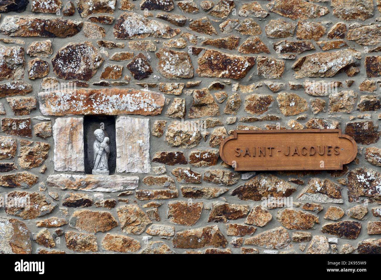 Nicchia con statua di saint in un muro di pietra naturale e segno di legno 'Saint-Jacques', Francia, Bretagna, Saint-Alban Foto Stock