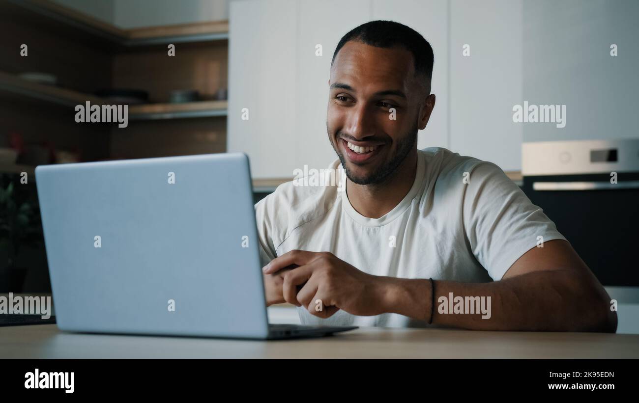 African Latina uomo maschio in cucina a casa ha remoto riunione virtuale parlare con la web cam di consultazione laptop online lavoro di studio insegnare e-learning Foto Stock