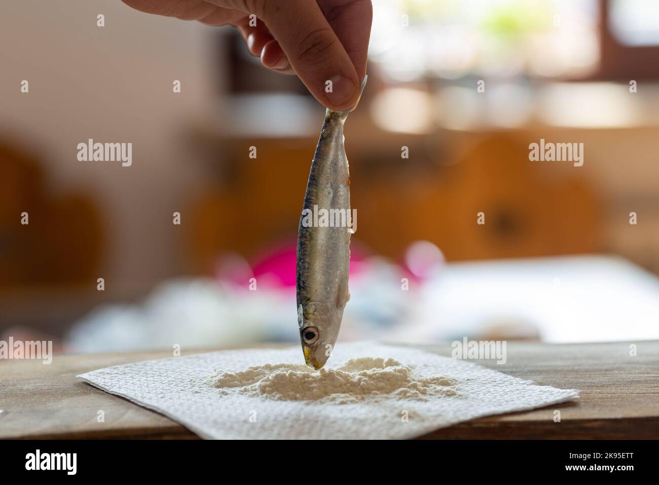 Mano che tiene una sardina dalla coda Foto Stock