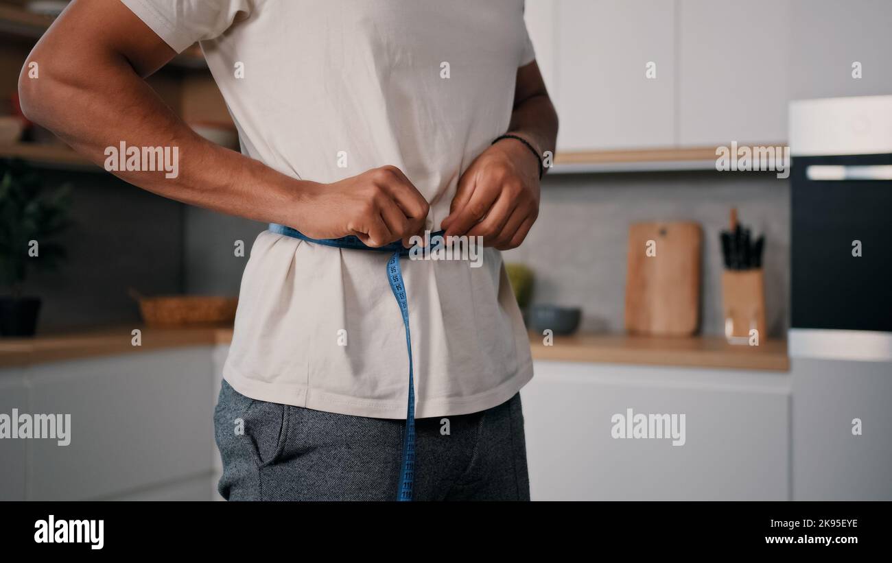 Irriconoscibile sportivo uomo sport uomo africano misura la vita con il nastro di misurazione controllare la perdita di peso allenamento allenamento sport dieta sana Foto Stock