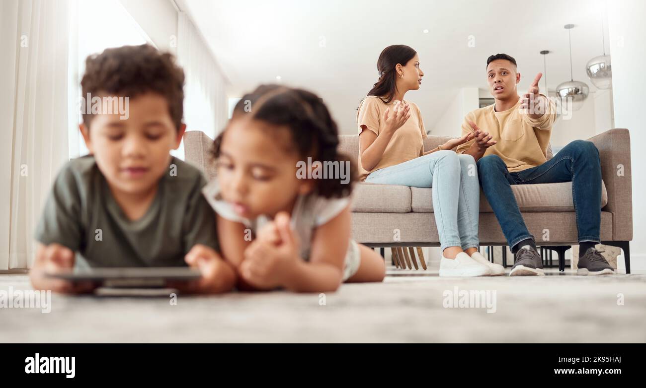 Madre, padre e disaccordo sul divano del soggiorno mentre i bambini giocano con un tablet sul pavimento a casa. Mama e papà combattono, discutono o. Foto Stock