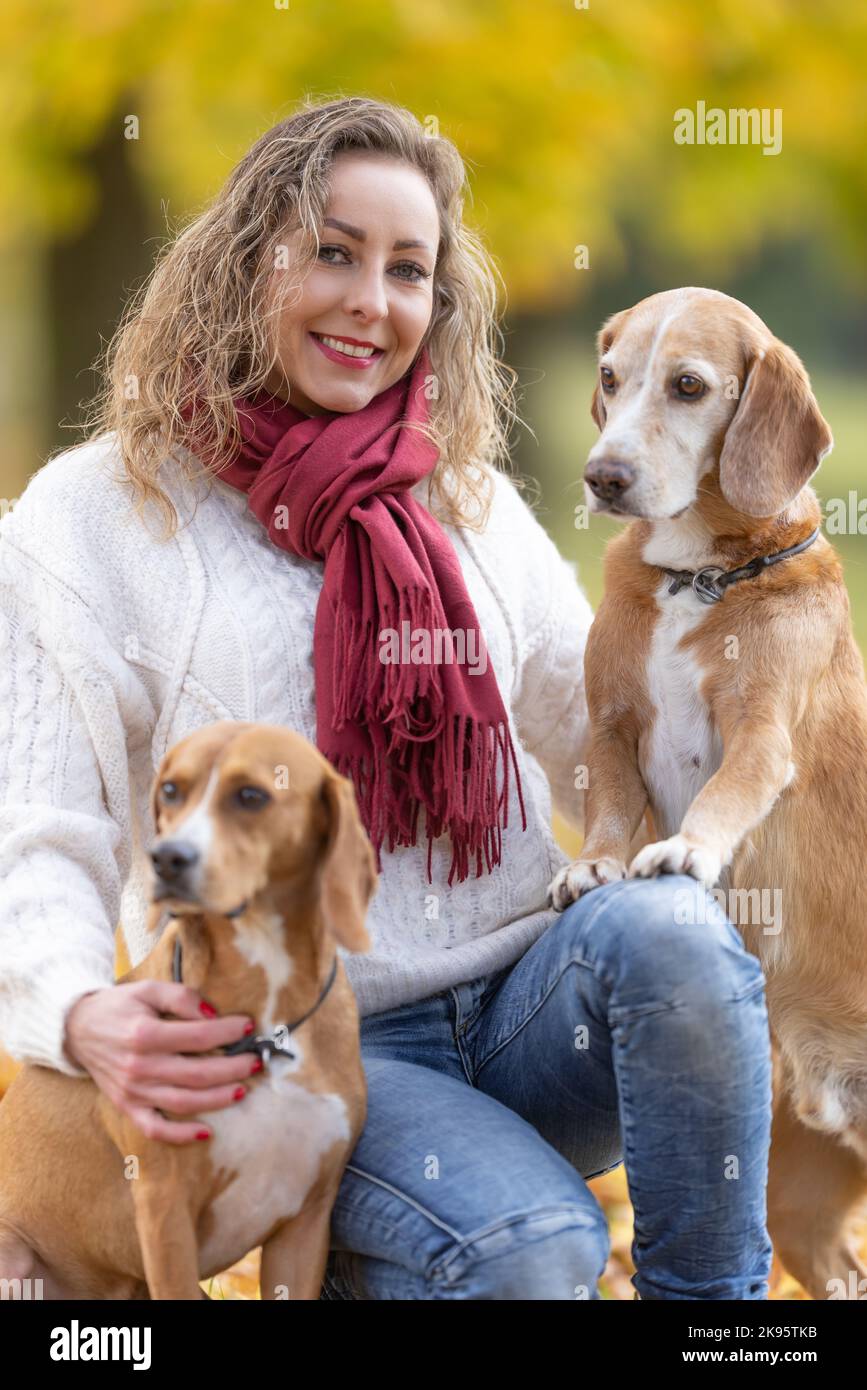 Ritratto di una giovane donna in un vestito autunnale con i suoi due animali domestici. Foto Stock