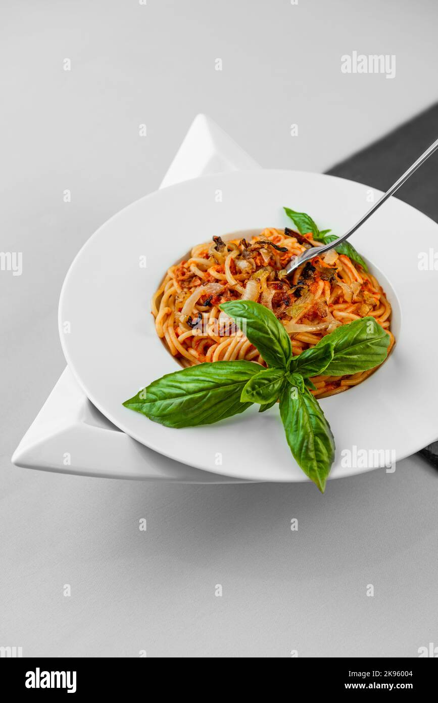 Spaghetti tonno pasta basilico piatto triangolare forma ardesia tavolo piuttosto appetitoso Foto Stock