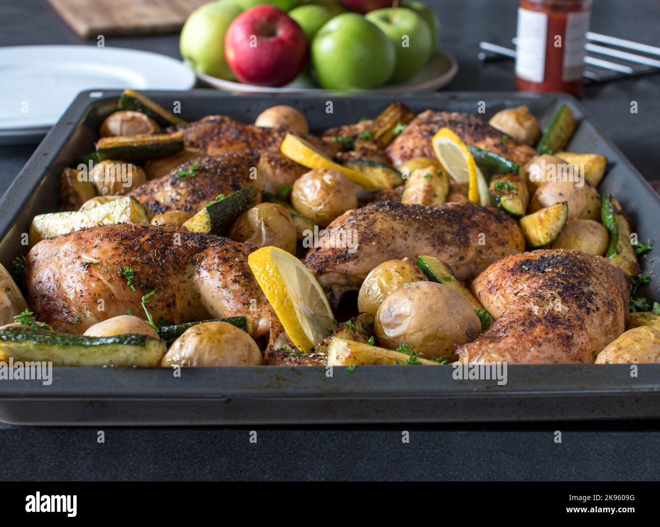 Cosce di pollo arrosto con verdure. Servito caldo su una teglia da forno sul tavolo da pranzo a casa. Vista frontale Foto Stock