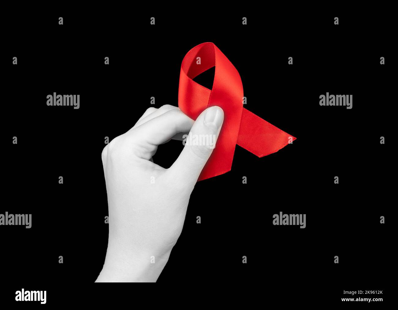 Nastro rosso in mano su sfondo nero per la giornata di sensibilizzazione sull'HIV AIDS, 1 dicembre. Foto di alta qualità Foto Stock