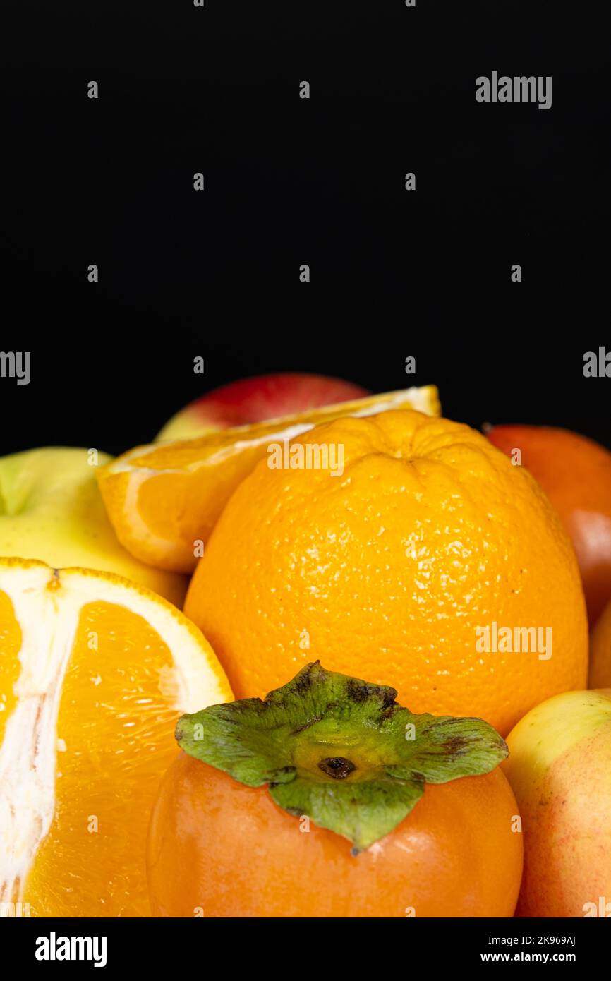 Frutti di colore arancio e giallo - mele, persimmoni e arance su sfondo nero Foto Stock