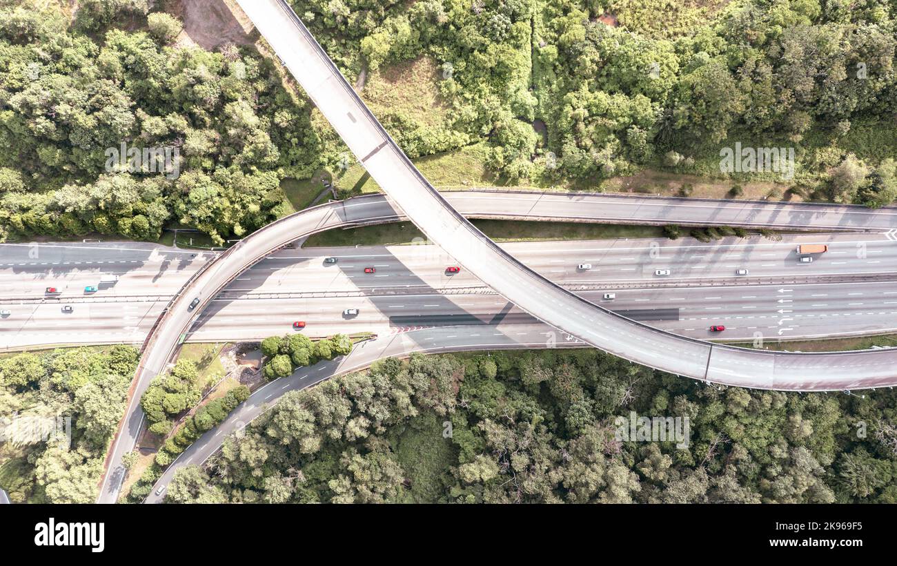 Vista aerea direttamente sopra un'autostrada a sei corsie. Vista dall'alto della strada asfaltata passa attraverso il campo e la foresta. Antenna. Berlina auto in auto da strada Foto Stock