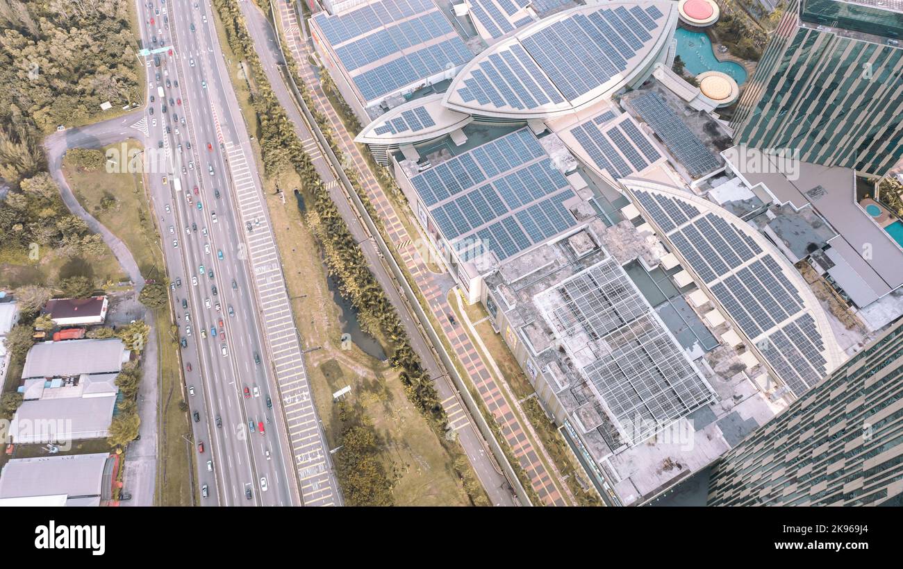 Malesia - 13 ottobre 2022: Vista aerea direttamente sopra un'autostrada. Vista dall'alto della strada asfaltata passa il centro commerciale con pannello solare sul tetto. Antenna p Foto Stock