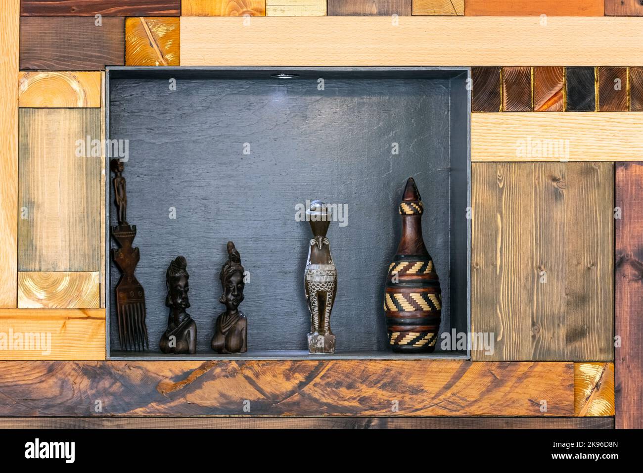 Nicchia con figurine e oggetti vari in una parete fatta di barre di diversi tipi di legno. Foto Stock