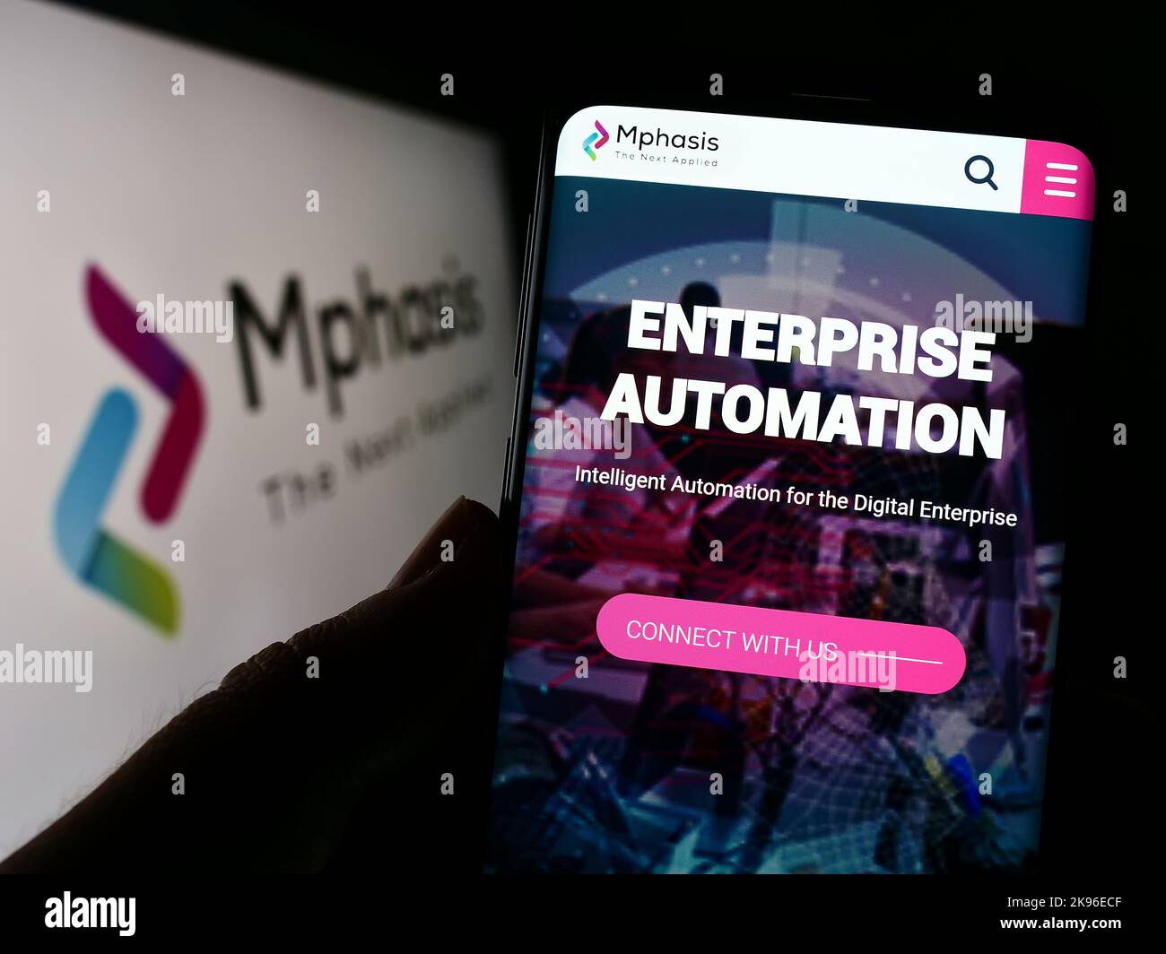 Persona che tiene il cellulare con il Web page della società di tecnologia dell'informazione Mphasis Limited sullo schermo con il logo. Messa a fuoco al centro del display del telefono. Foto Stock