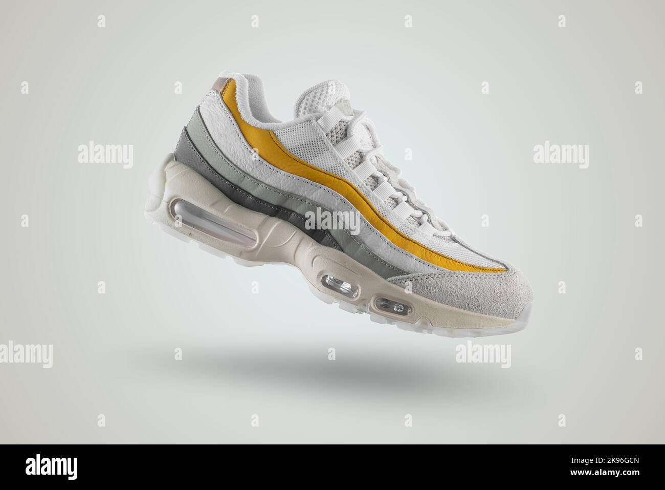 Sneaker grigio chiaro con dettagli gialli su sfondo isolato bianco Foto Stock