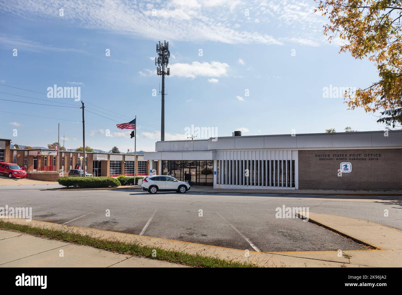 BREVARD, NORTH CAROLINA, USA-9 OTTOBRE 2022: Ufficio postale degli Stati Uniti-edificio, bandiera, parcheggio, torre cellulare. Reparto antincendio in background. Foto Stock