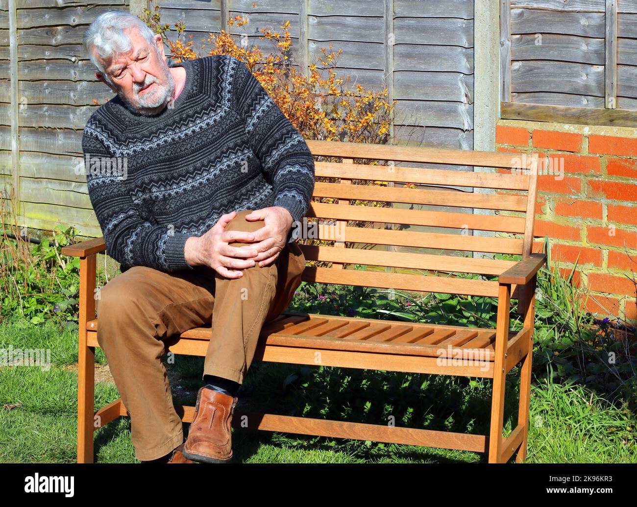 Uomo anziano o anziano che soffre di dolore con artrite al ginocchio o alla gamba. Tenendo le gambe in agonia. Foto Stock