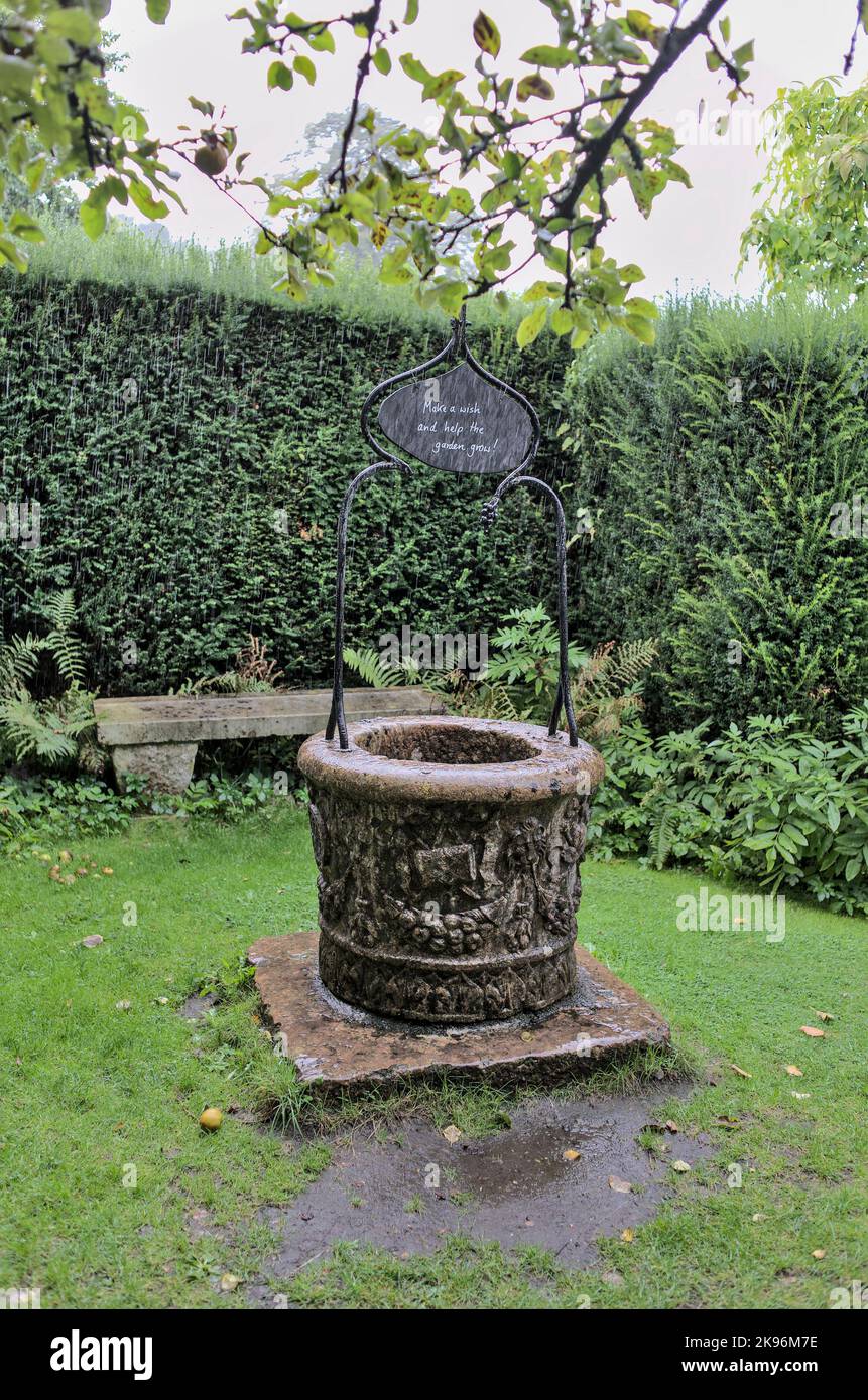 Pietra che desidera bene e panca in Gilbert Whites Hampshire giardino Foto Stock