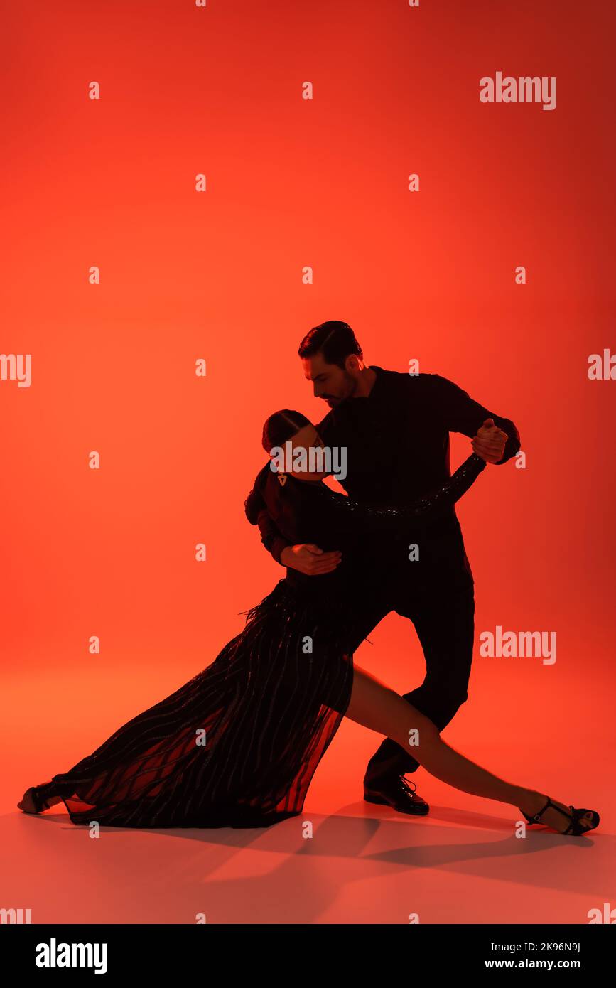 Silhouette di uomo in tuta tango danzante con donna in abito su sfondo rosso Foto Stock