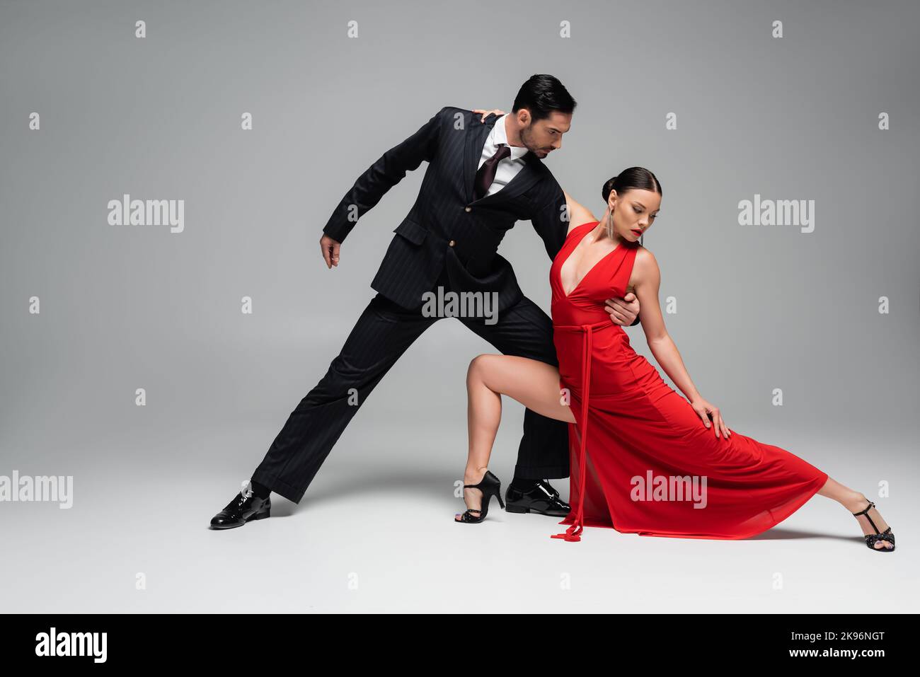 Uomo in tuta che abbraccia il compagno mentre ballava tango su sfondo grigio Foto Stock