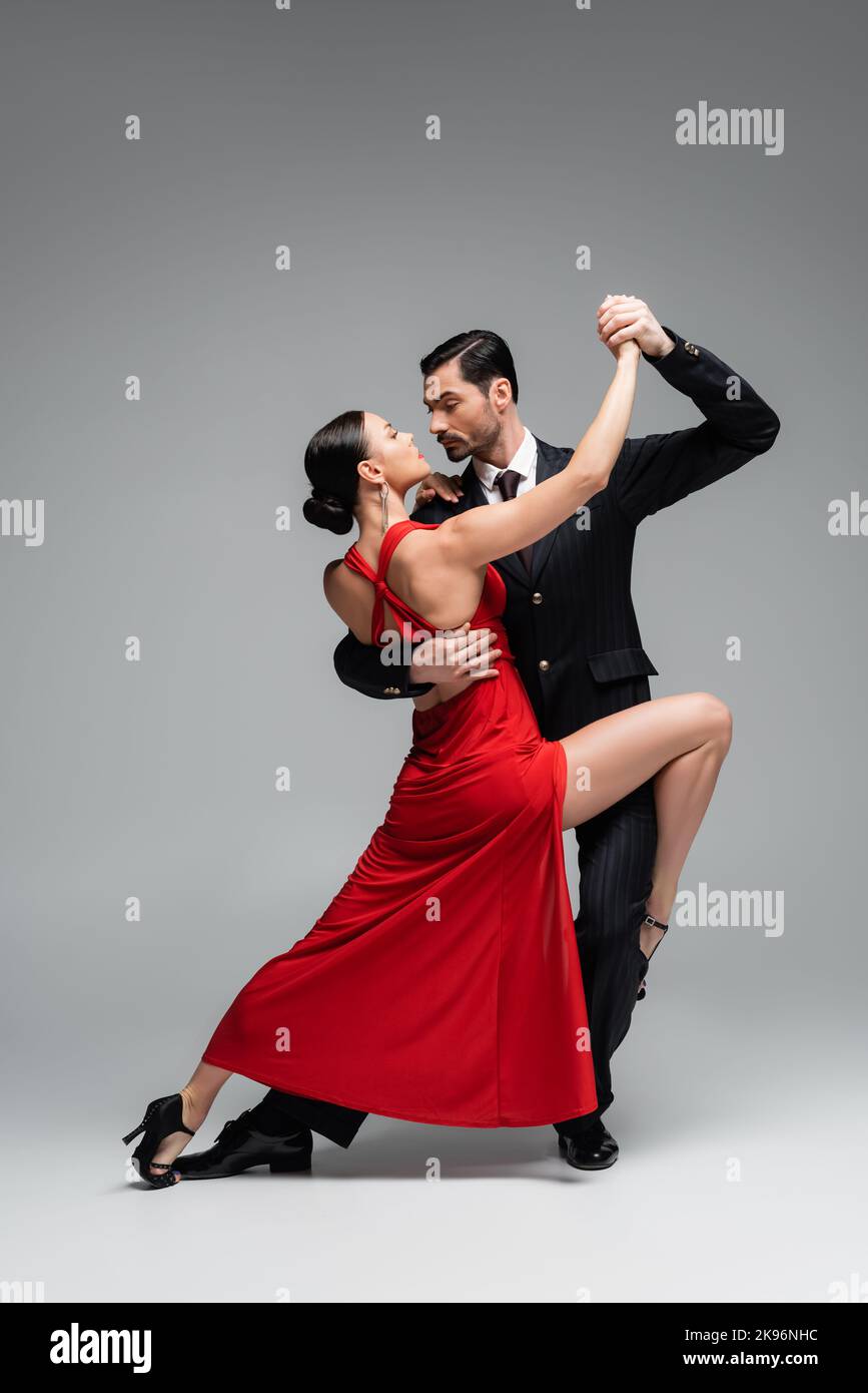 Lunghezza intera di elegante coppia danzante tango su sfondo grigio Foto Stock
