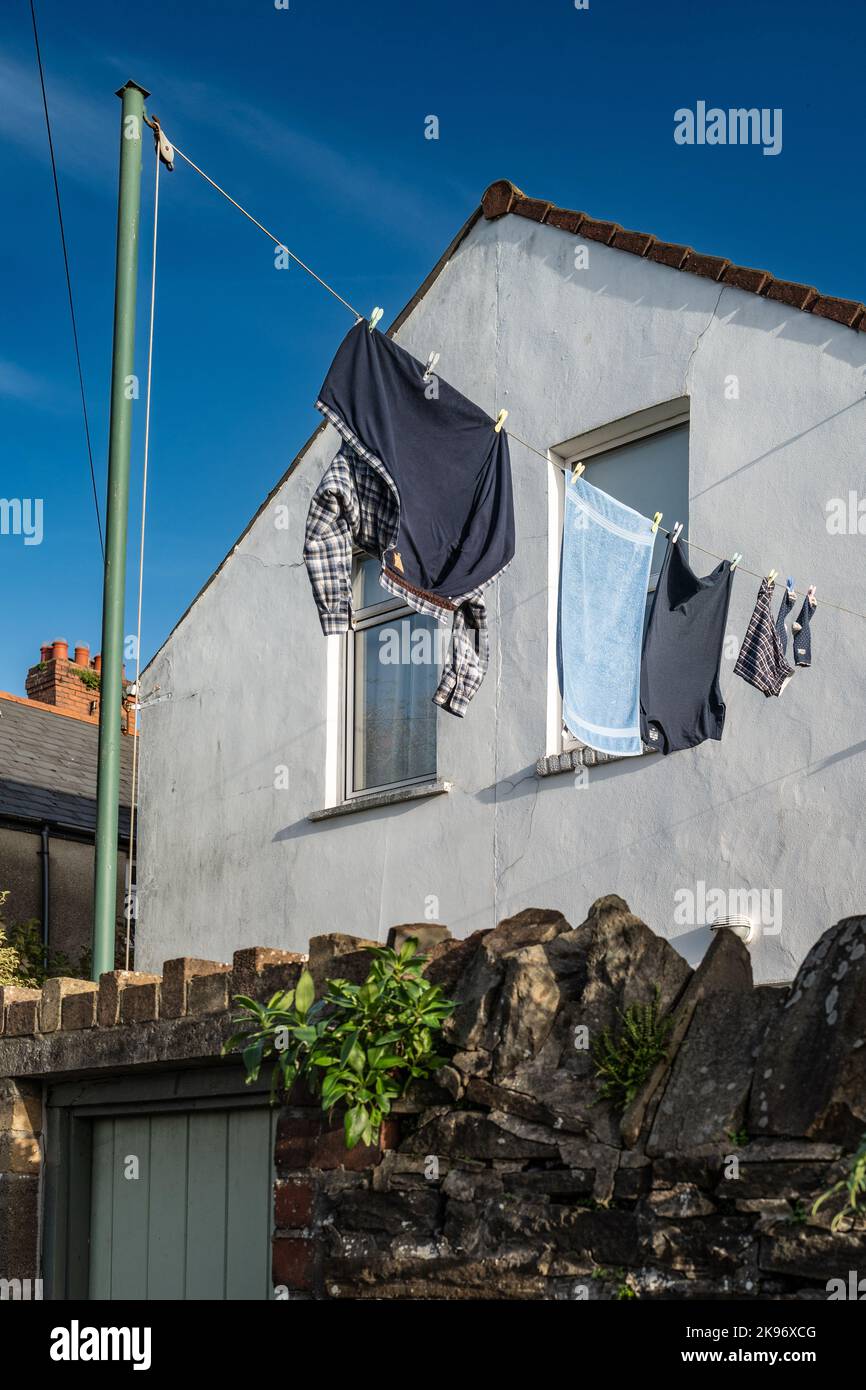 Lavaggio appeso ad asciugare su una linea di vestiti fuori di una casa a schiera a Cardiff, Galles. Camicie colorate, casa e cielo Foto Stock