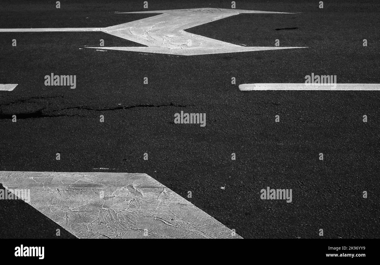 Segnaletica stradale con linee bianche e frecce su asfalto scuro, astratto trasporto sfondo foto Foto Stock