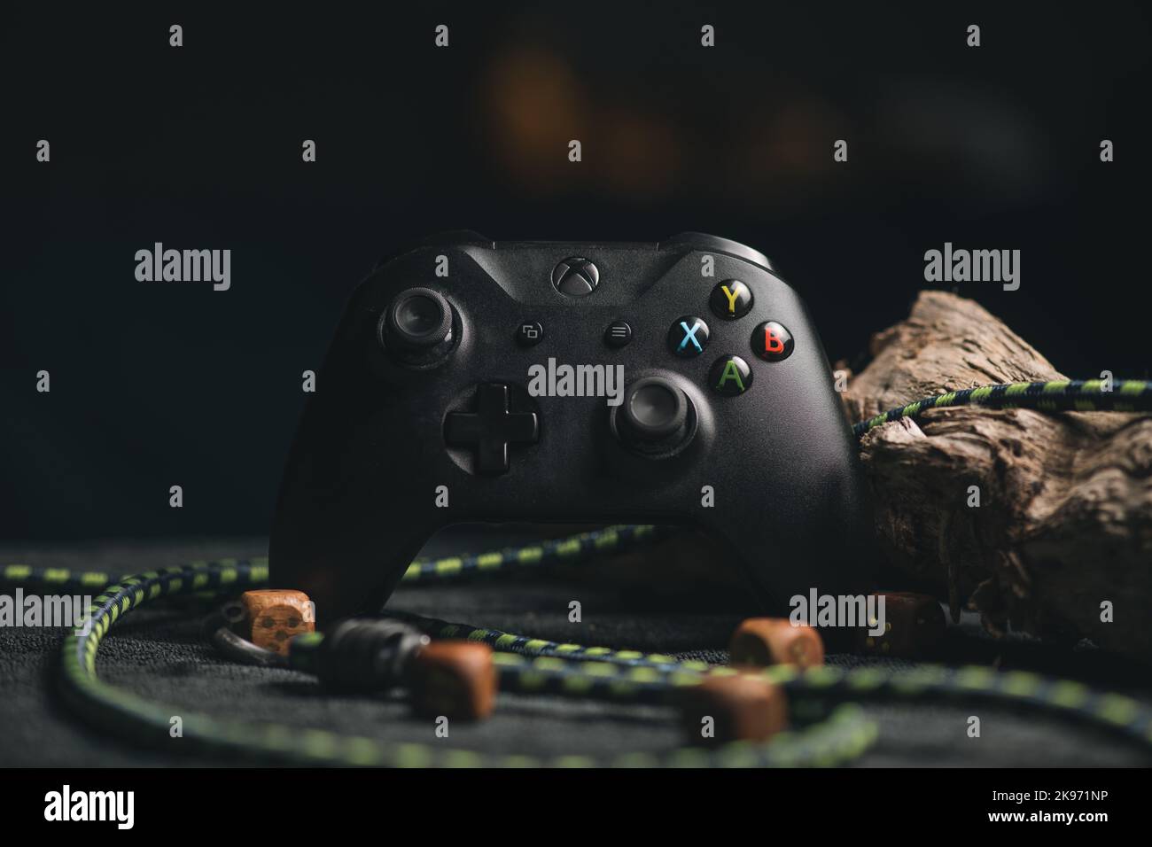 Una messa a fuoco selettiva di Microsoft Xbox serie X con un filo verde e un legno sul retro Foto Stock