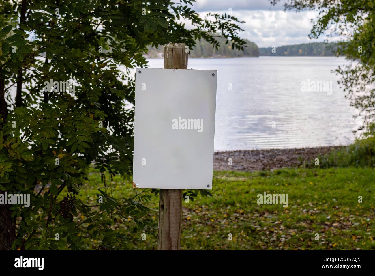 Cartello bianco vuoto accanto ad una spiaggia in autunno Foto Stock