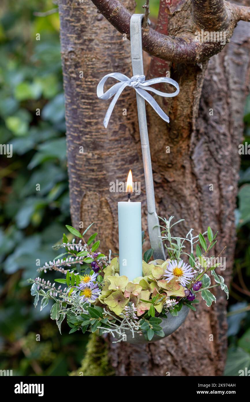 sistemazione con candela e fiori in vecchio mestolo in giardino Foto Stock
