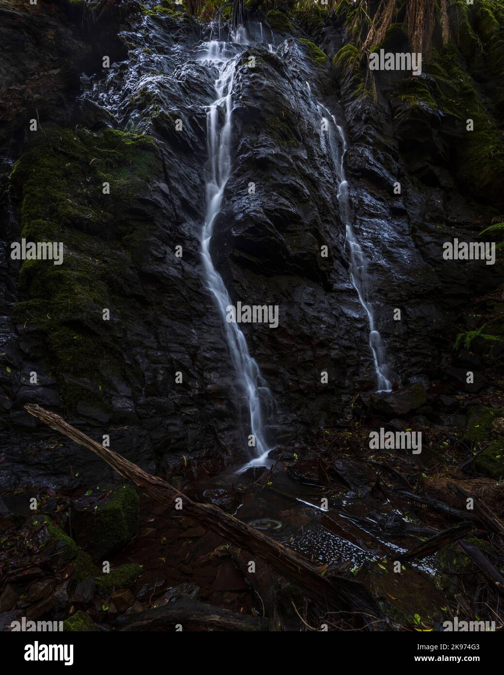 Uno scatto verticale di un ruscello di cascata circondato da muschio Foto Stock