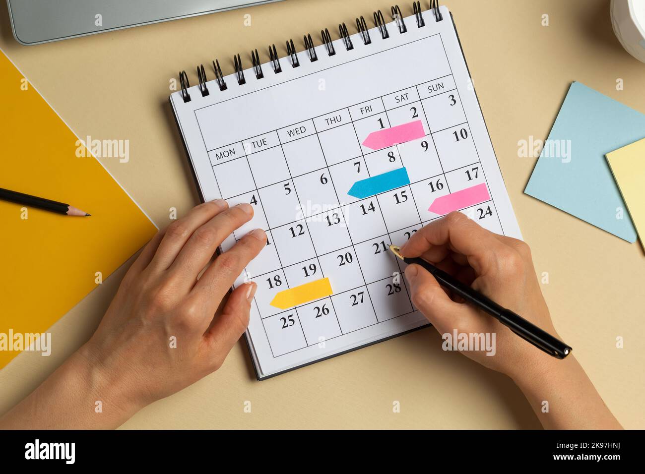 Mani di una donna che pianifica e che segna le date del calendario delle riunioni aziendali sul calendario. Foto Stock