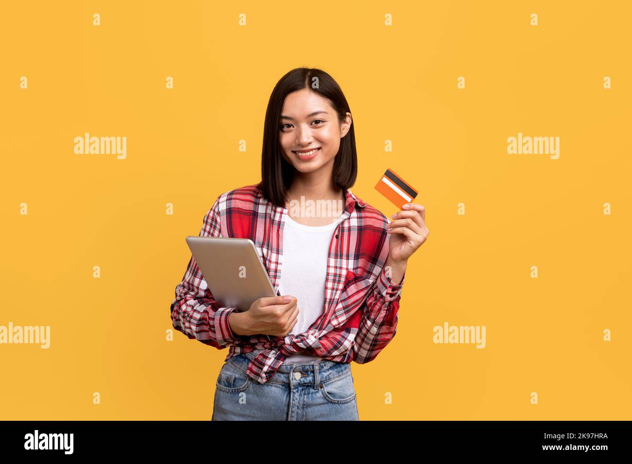 Concetto di shopping online. Donna cinese felice che tiene il tablet digitale e mostra la carta di credito, ordinando gli acquisti Foto Stock
