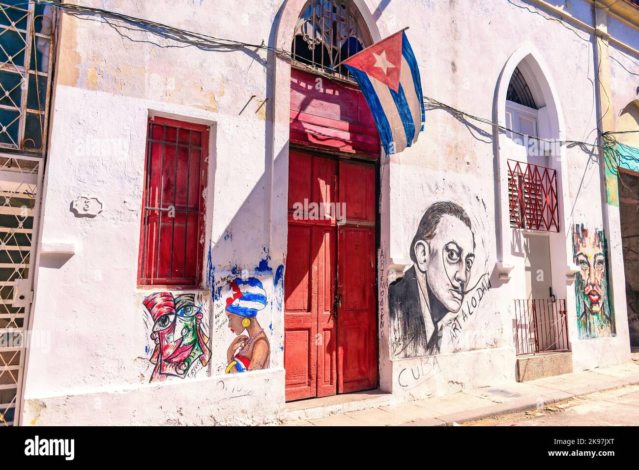 Facciata di un edificio con dipinti urbani e una bandiera cubana in cima alla porta d'ingresso Foto Stock
